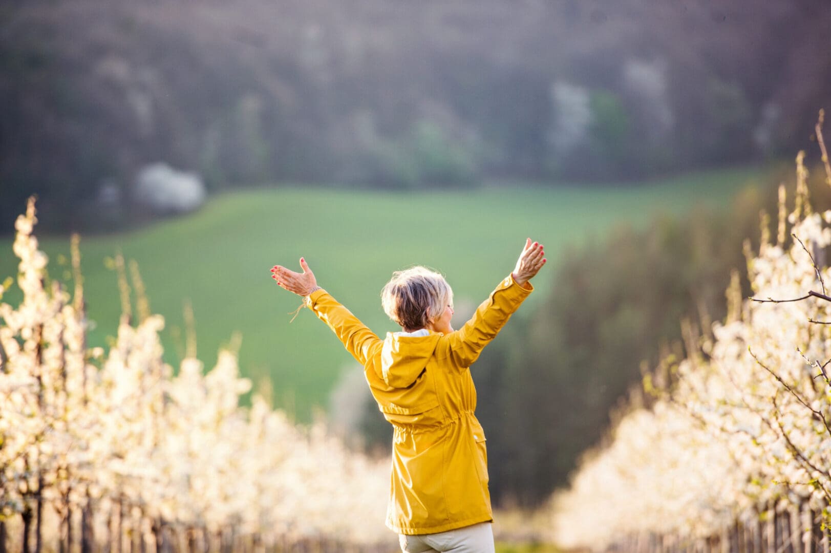 A person in yellow jacket standing on top of grass covered field.